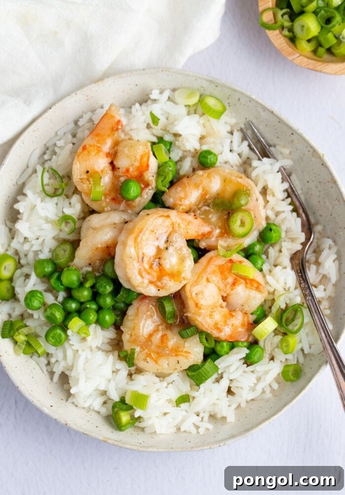 Shrimp with lobster sauce on a bed of rice in a white bowl with a fork