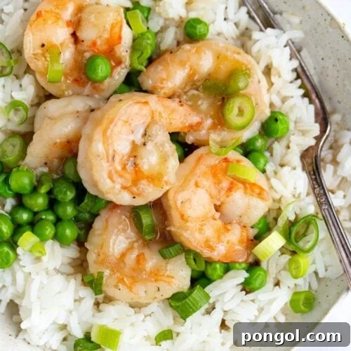 Shrimp with lobster sauce and peas on a bed of rice in a white bowl