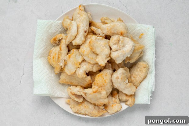 Chicken pieces cooking in a hot skillet with vegetable oil.