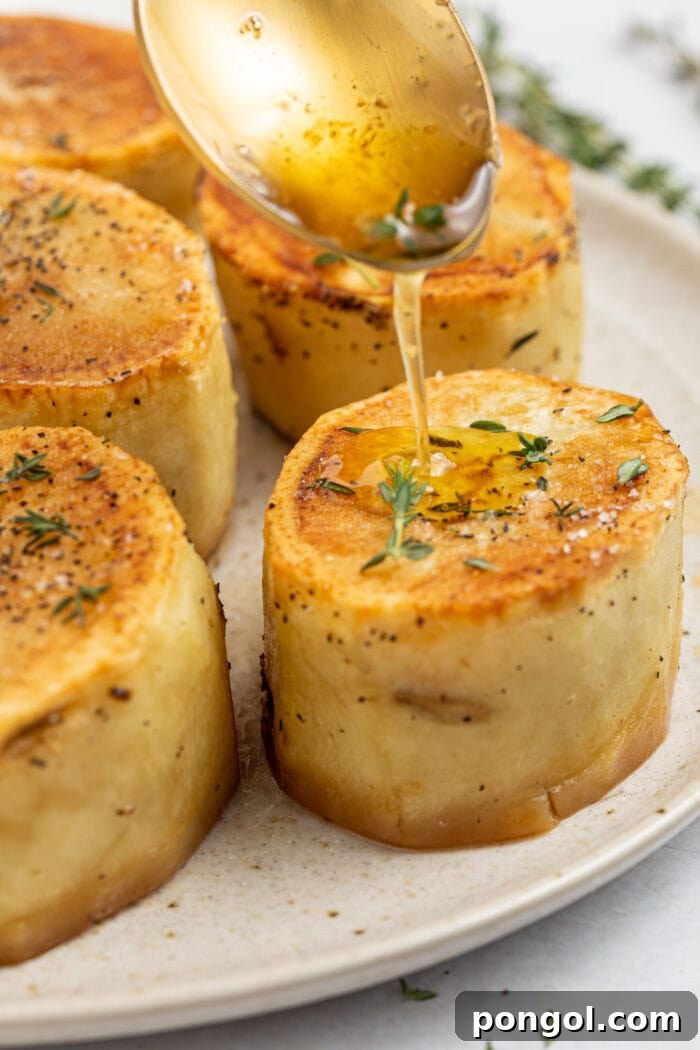 Golden Glazed Fondant Potatoes 2 Rich thyme butter sauce being drizzled over perfectly golden and crispy fondant potatoes, ready to serve.