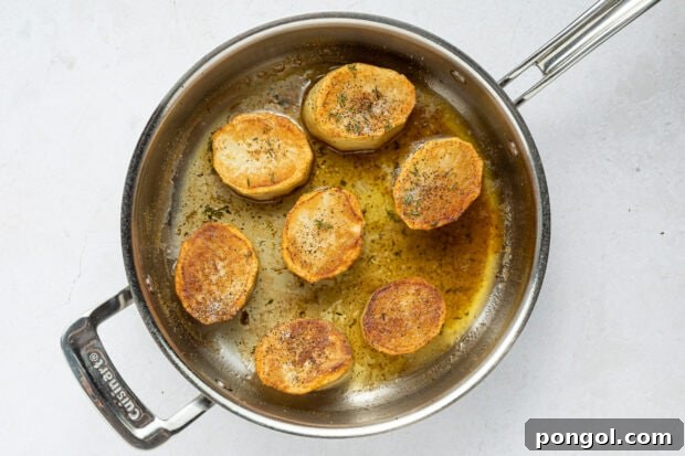 Golden Glazed Fondant Potatoes 9 Fondant potatoes in skillet with butter and broth, ready for oven