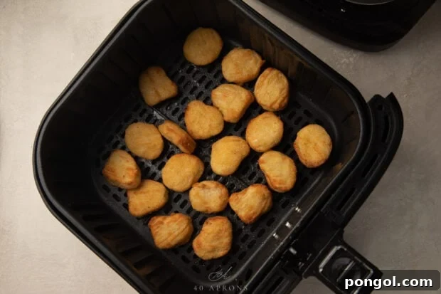 Frozen chicken nuggets in an air fryer basket
