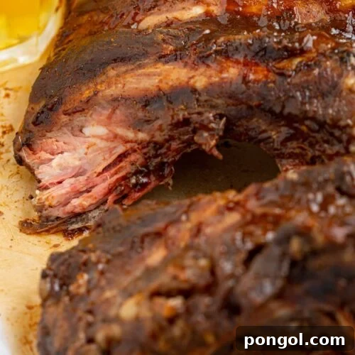 beef ribs on parchment paper with a glass of beer on the side