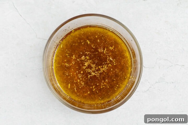 Prepared vinaigrette for Mediterranean chickpea salad in a small glass mixing bowl.