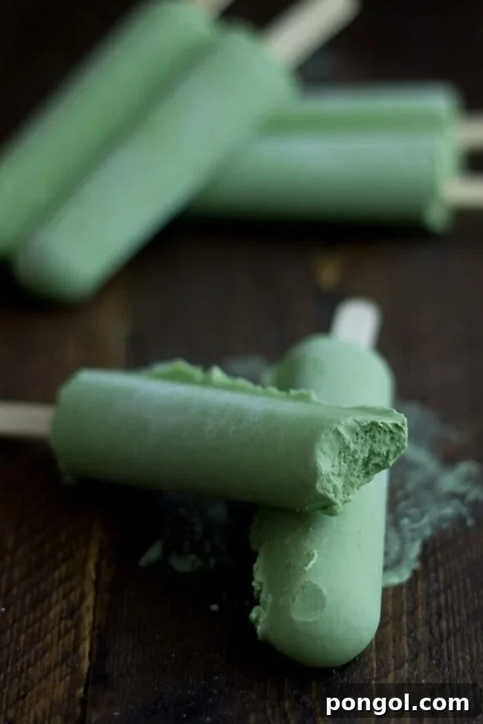 Green tea coconut popsicles, with one bite missing from a popsicle stacked on another popsicle.