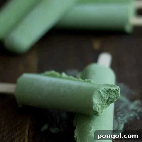 Green tea coconut popsicles, with one bite missing from a popsicle stacked on another popsicle.