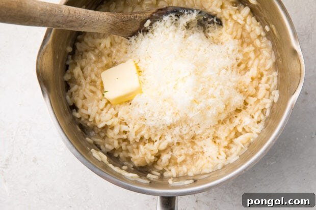 Arborio rice in a large saucepan, being finished with Parmesan cheese and butter, creating a rich and creamy texture with a wooden spoon.