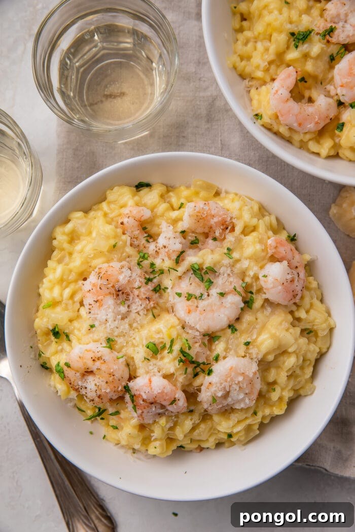 Creamy Parmesan Shrimp Risotto 3 An overhead shot showcasing a large bowl of golden shrimp risotto, with a serving spoon and a second, smaller bowl of risotto in the background, creating a tempting culinary scene.
