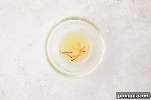 Chicken stock and saffron infusing in a small glass bowl, preparing to add rich flavor and color to the risotto.