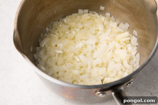 Finely chopped onions sautéing in a large saucepan, gently softening in butter for the risotto base.