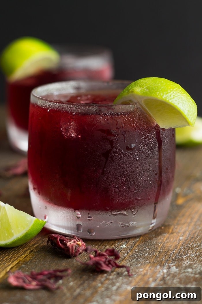 Close-up of freshly brewed Hibiscus Tea with lime slices, highlighting its vibrant color and refreshing appeal.