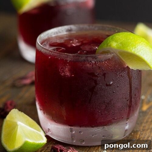 A chilled glass of homemade Hibiscus Tea (Agua de Jamaica) with ice and lime slices, ready to be enjoyed.