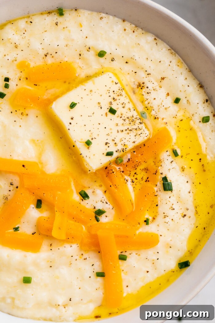 Creamy Cheese Grits Perfection: Stone-Ground and Quick Methods 2 Overhead, close-up view of a bowl of grits with shredded cheese, a pat of butter, and black pepper.