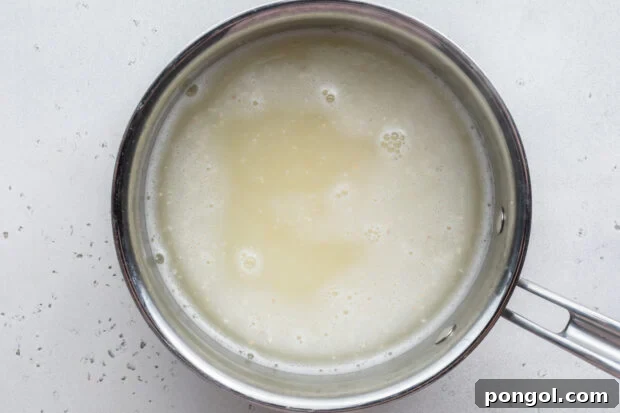Creamy Cheese Grits Perfection: Stone-Ground and Quick Methods 10 Overhead view of grits and water in large silver saucepan.