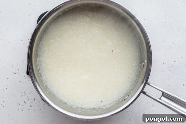 Creamy Cheese Grits Perfection: Stone-Ground and Quick Methods 11 Overhead view of grits and water in large silver saucepan.