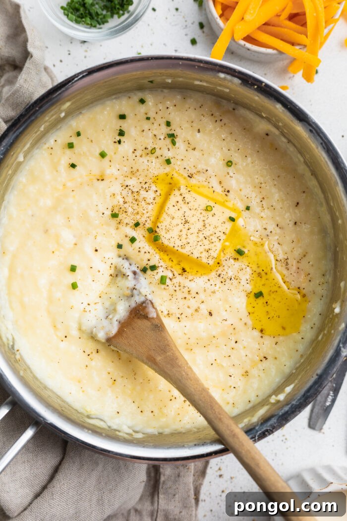 Creamy Cheese Grits Perfection: Stone-Ground and Quick Methods 3 Overhead view of creamy grits in a large silver saucepan with cheese and black pepper.