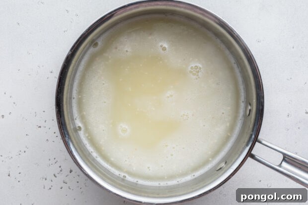 Creamy Cheese Grits Perfection: Stone-Ground and Quick Methods 6 Overhead view of grits and water in large silver saucepan.