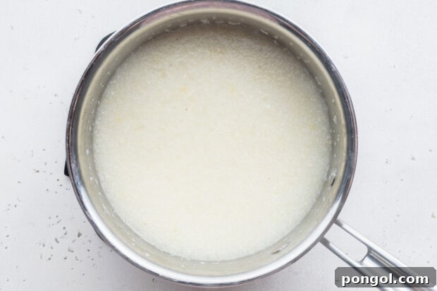 Creamy Cheese Grits Perfection: Stone-Ground and Quick Methods 7 Overhead view of grits and water in large silver saucepan.