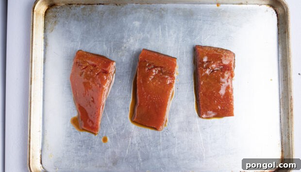 Perfect Miso Glazed Salmon 8 Miso salmon fillets neatly arranged on a baking sheet, prepped for broiling.