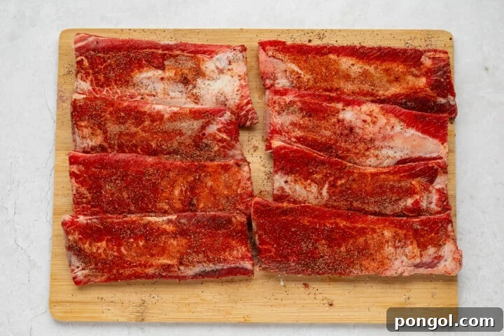 Seasoning beef back ribs thoroughly with a homemade dry rub mixture before baking.