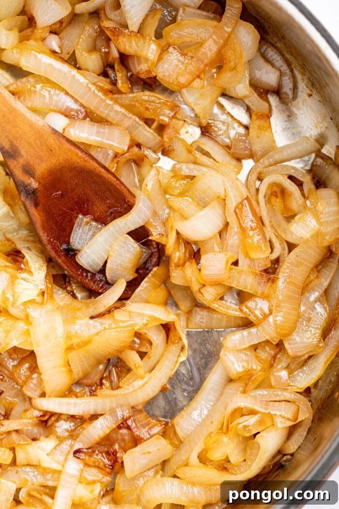 sauteed onions in a skillet with a wooden spoon