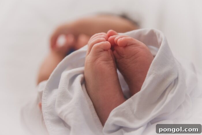 Closeup of baby feet in a blanket with baby's head and arm out of focus in the background - natural birth with epidural. This image evokes comfort and new beginnings.