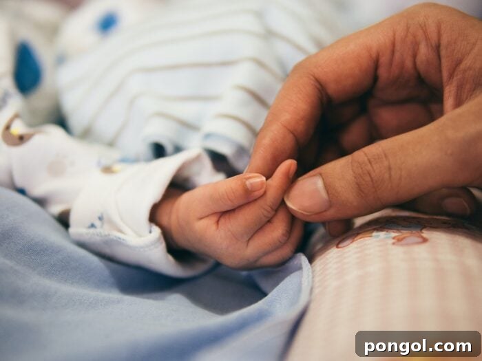 Woman holding baby's hand - natural birth with epidural. This intimate moment highlights the joy and connection of childbirth.