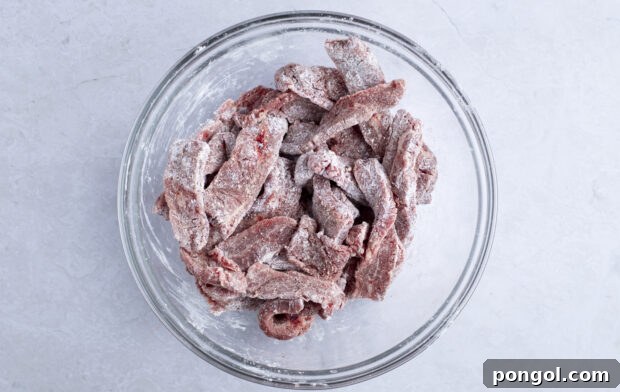 Beef and cornstarch in large glass mixing bowl