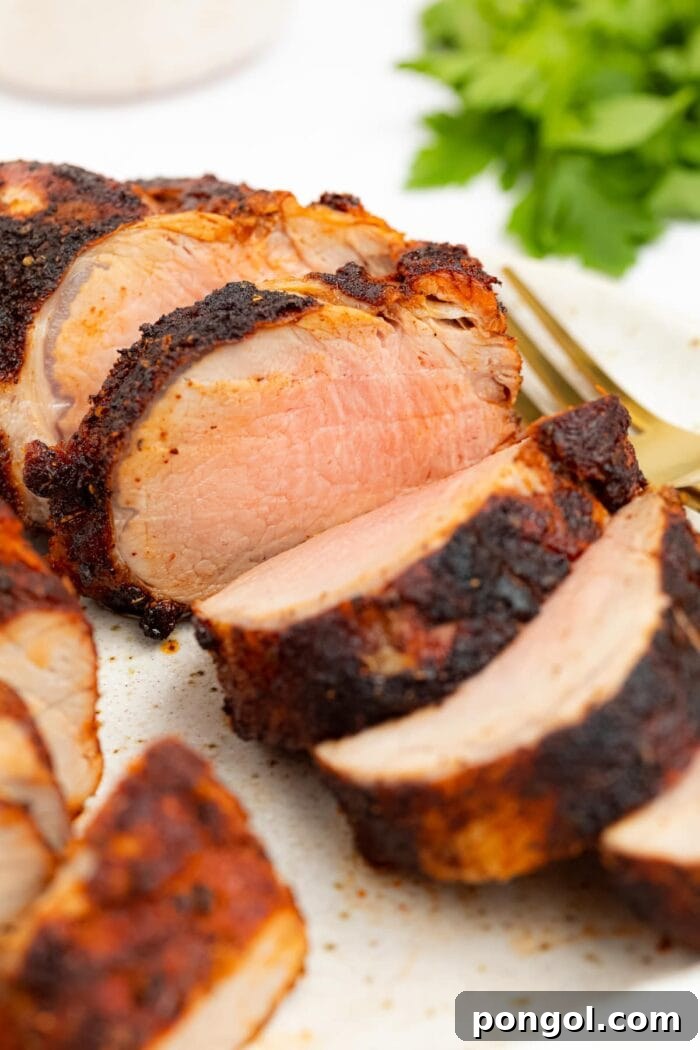air fryer pork tenderloin on a plate with a fork and fresh parsley on the side