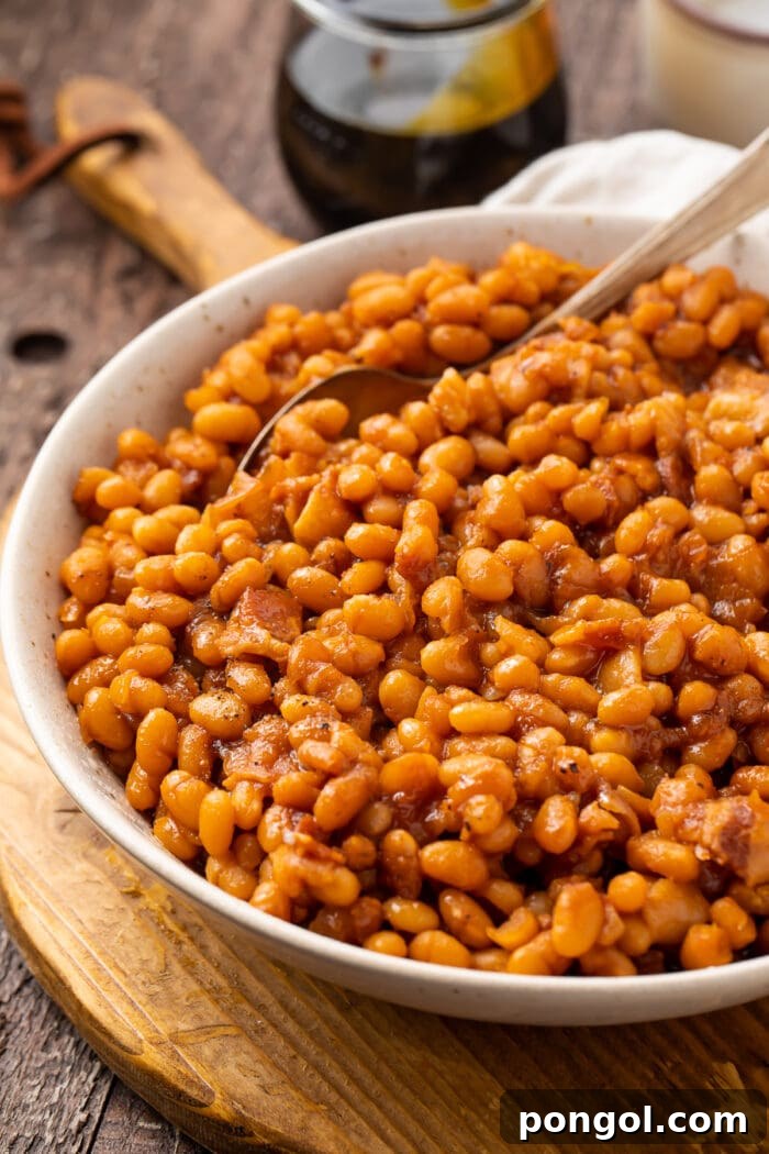 Angled photo of Instant Pot baked beans in a white bowl on a wooden board
