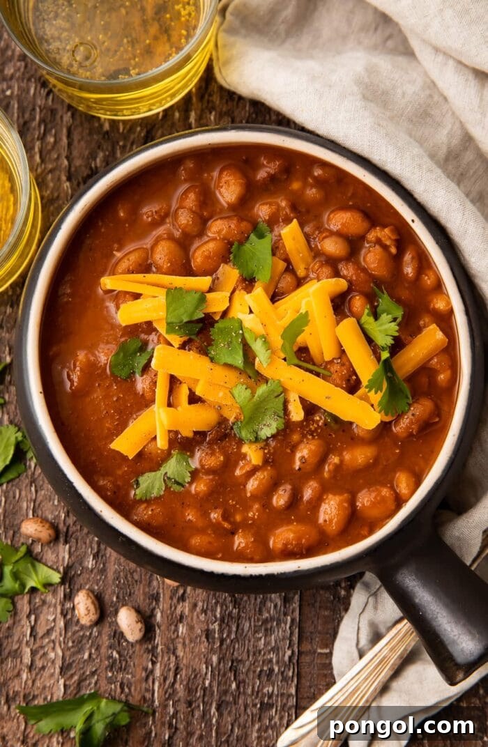 Smoky Rancher's Beans 3 Overhead photo of ranch style beans in a black bowl on a wooden table