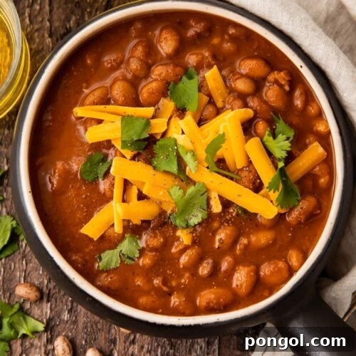 Smoky Rancher's Beans 4 Overhead photo of ranch style beans in a black bowl on a wooden table