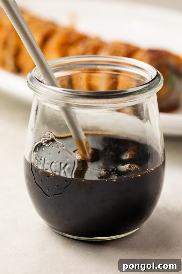 Sweet Unagi Glaze 3 Homemade eel sauce simmering gently in a small white saucepan on the stove, showing its rich, dark color and bubbling texture.