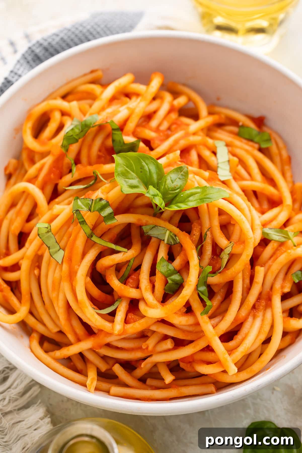 Classic Pomodoro Perfection 3 Close-up, overhead view of a white bowl of spaghetti swirled with red pomodoro sauce and topped with fresh basil leaves.