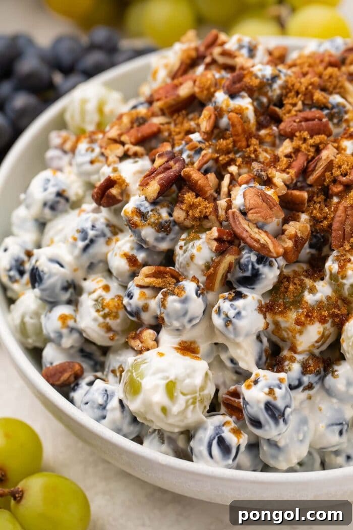 Creamy grape salad topped with pecans and brown sugar, ready to serve