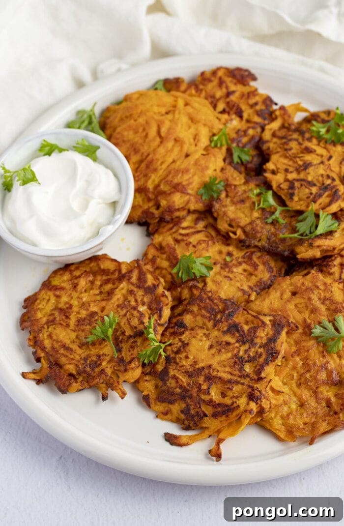 A serving of sweet potato hash browns on a white plate, garnished with a dollop of sour cream