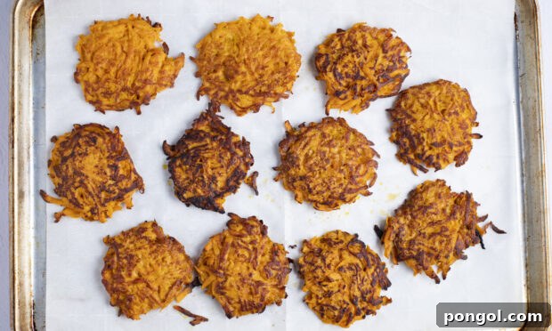 Sweet potato hash browns arranged on a baking sheet lined with parchment paper before final baking in the oven