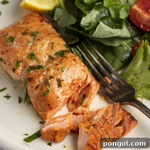 Delicious broiled salmon on a plate next to a small salad