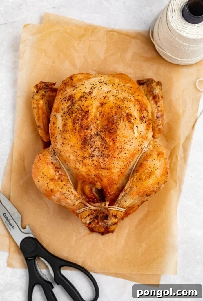 showing how to truss a chicken on two sheets of parchment paper with scissors and butcher's twine