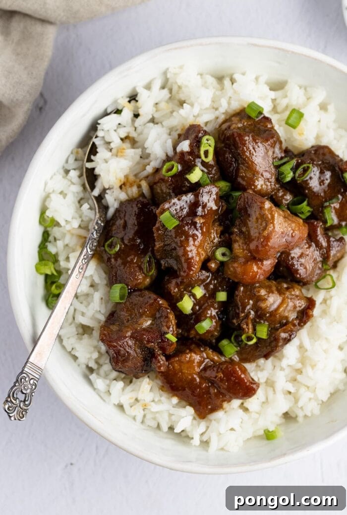 Pork adobo on top of white rice in a serving bowl