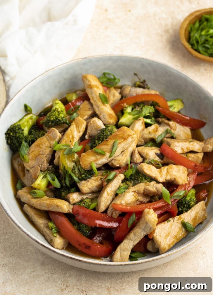 Close-up of succulent Pork Stir Fry, rich with tender pork strips and vibrant, crisp vegetables, served in a white bowl without rice, showcasing its delicious texture and color.