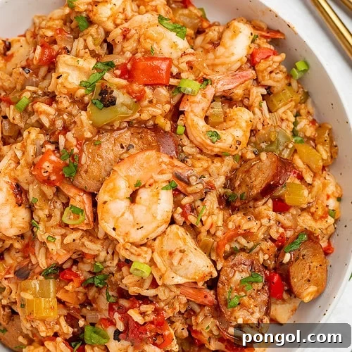Overhead photo of a large white bowl holding Instant Pot jambalaya with rice, shrimp, sausage, and veggies.