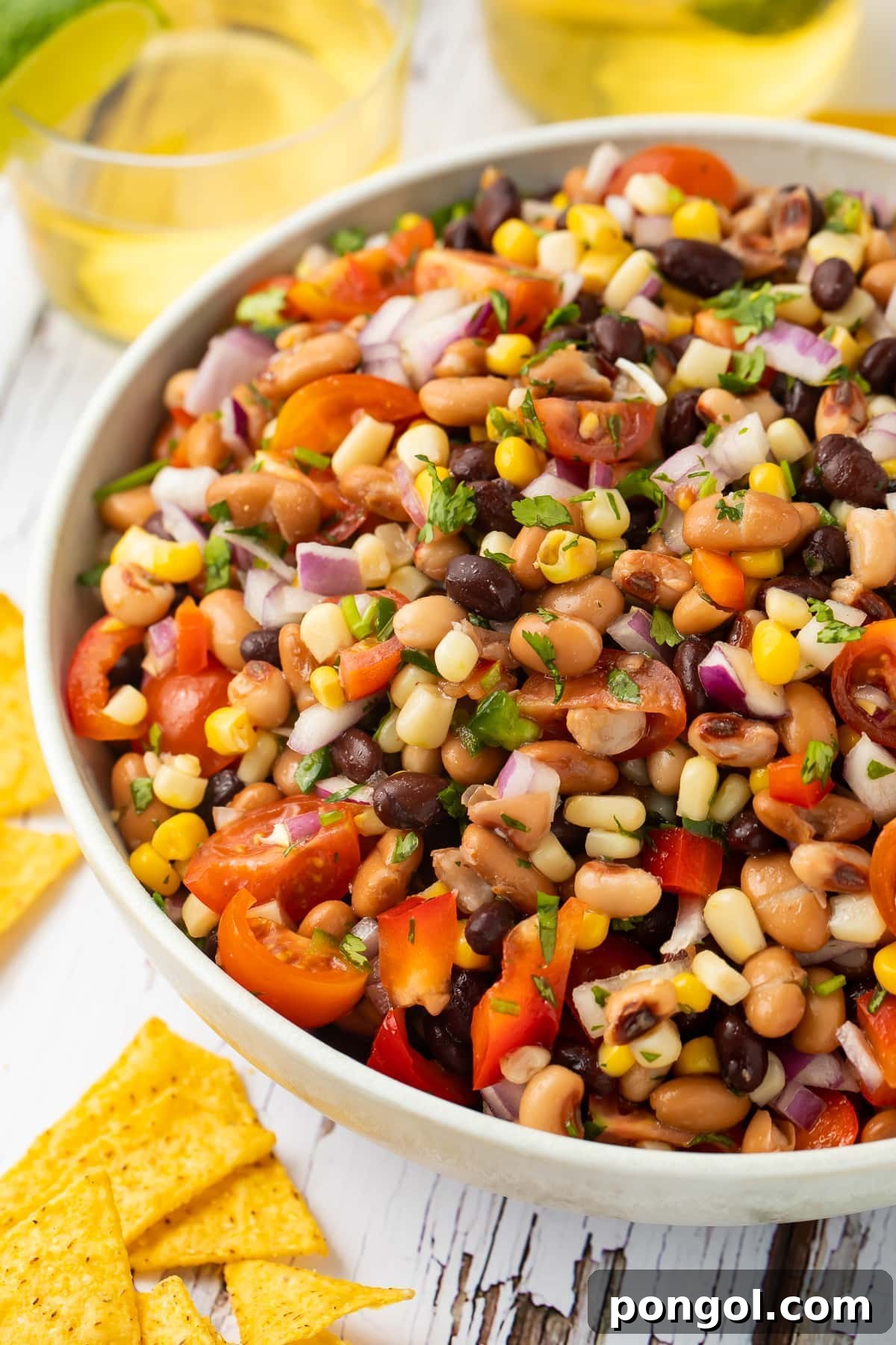 Texas caviar in a white bowl surrounded by yellow corn tortilla chips.