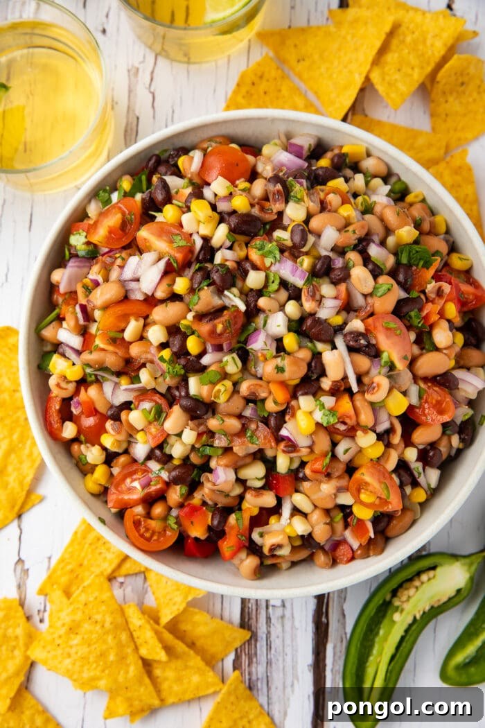 Overhead view of Texas caviar in a large bowl surrounded by chips and jalapenos
