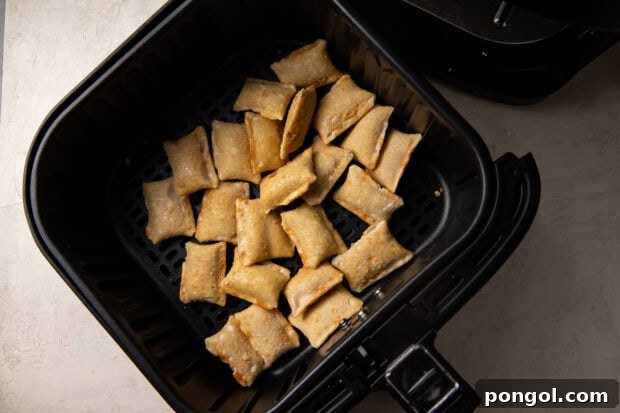 Frozen pizza rolls laid out in a single layer in the air fryer basket, ready for cooking.