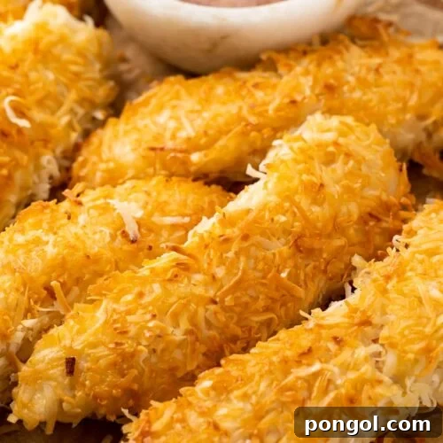 Crispy beer-battered coconut chicken on a plate next to orange-horseradish sauce