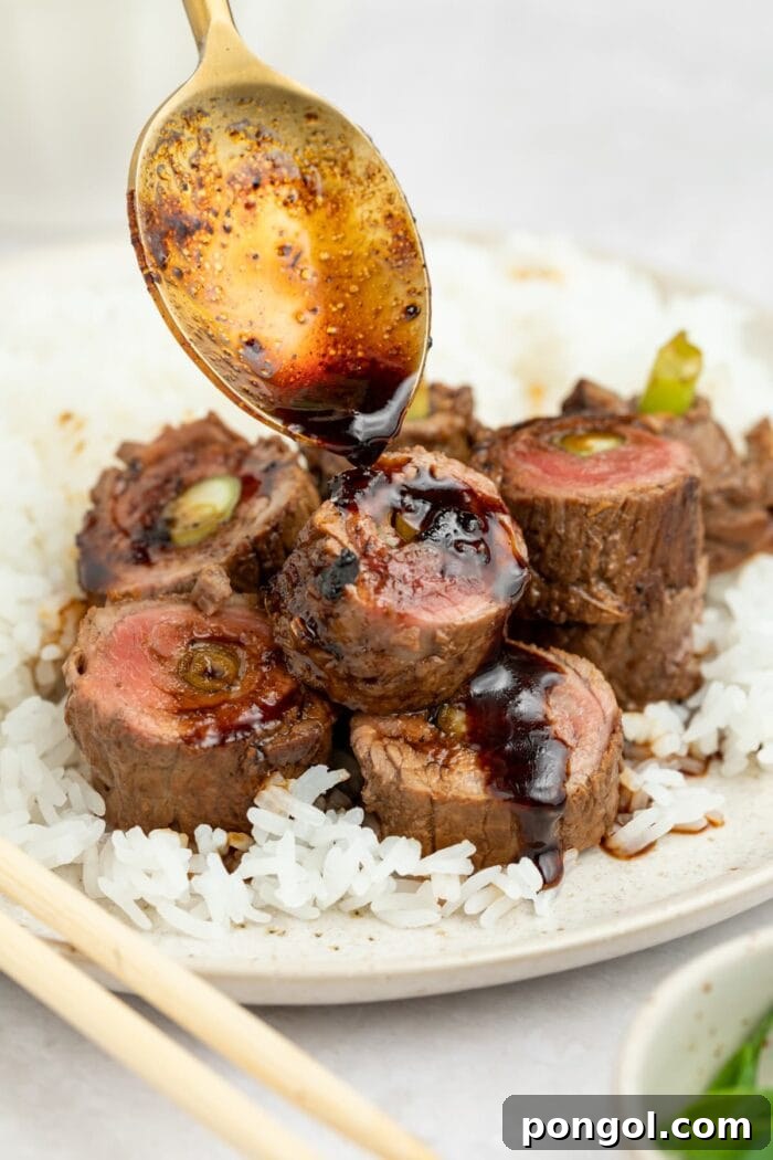 Savory-sweet sauce being spooned over beautifully seared beef negimaki rolls, ready to serve.