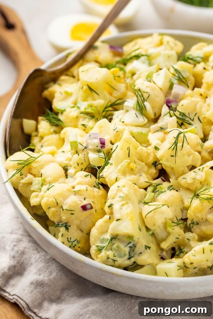 Cauliflower potato salad in a large bowl with a spoon