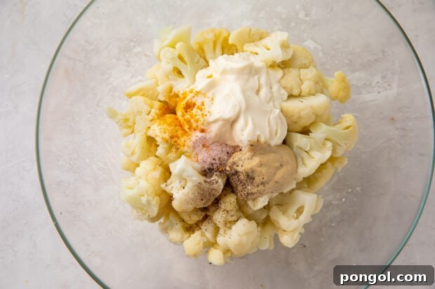 Cauliflower potato salad ingredients in a glass mixing bowl