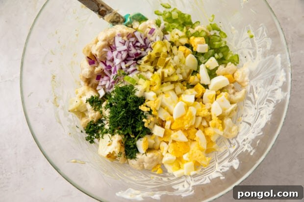 Cauliflower potato salad ingredients in a glass mixing bowl